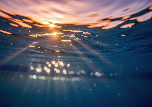 Underwater View of Ocean Surface with Golden Sun Rays and Bokeh Light at Sunset photo