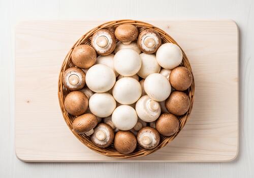 Assortment of Fresh White and Brown Button Mushrooms in a Wicker Basket on a Wooden Board, Top View photo