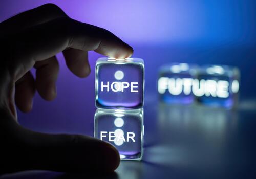 Hand on stacked dice showing 'HOPE' and 'FEAR', representing choices for the future photo