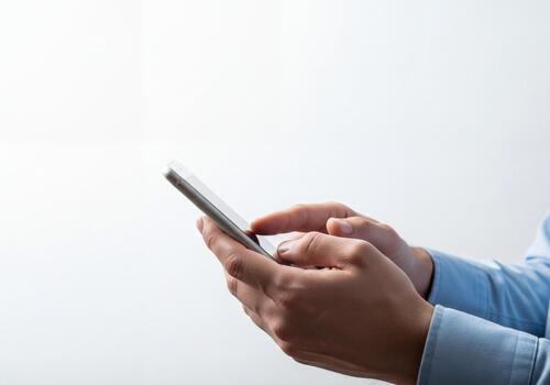Man's hands using a modern smartphone with a blank screen on a clean white background photo