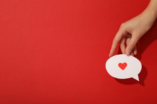 Paper message icon with heart in hand on red background, space for text photo