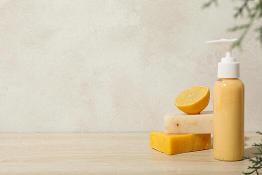 Soap in bottle with dispenser, bars of soap and lemon on beige background, space for text photo