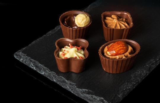 Chocolates with cream and nuts on a slate sorting board. Assorted chocolate on black isolated background photo