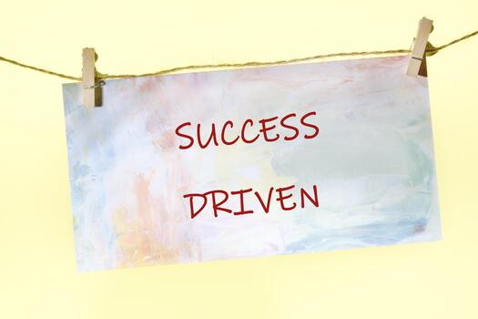 A colorful sign displays the phrase Success Driven, hanging from a string in a bright, cheerful setting. This inspiring message encourages determination and growth in an inviting atmosphere photo