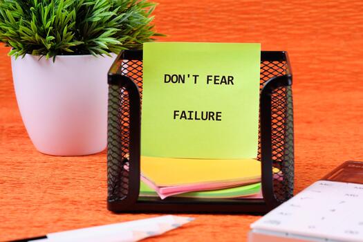 Concept text DO NOT FEAR FAILURE written on colorful stickers in a black mesh holder photo
