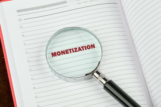A magnifying glass highlights the term monetization in a notebook, indicating a focus on strategies for generating revenue in business photo