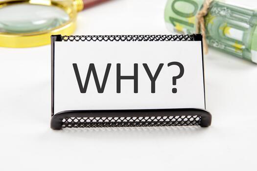 WHY the text on the business card next to the roll of money with a magnifying glass in the background is out of focus on a white background photo