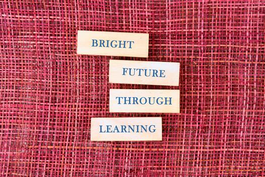 Four wooden blocks arranged on a textured background convey an inspiring message about the importance of learning for a bright future, inviting curiosity and hope photo