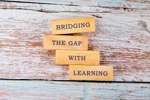 Wooden blocks display the message about bridging the gap with learning. The scene features a rustic wooden background, symbolizing the importance of education in personal development photo