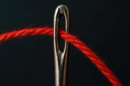 Red Thread Passing Through Eye Of Metal Needle On Dark Background photo