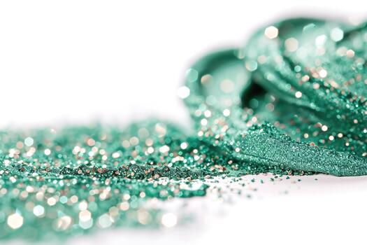 Fine green glitter swirls and sparkles on a white surface, creating a beautiful display during a crafting session. The shimmering particles reflect light, adding a festive touch photo