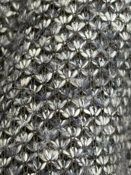 Knitted texture in gray and white wool forming intricate pattern, ideal for winter clothing background photo