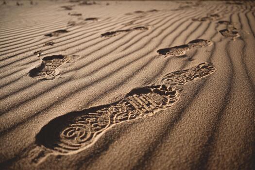 Footprints create a unique pattern on a wind-swept sand dune under sunlight photo