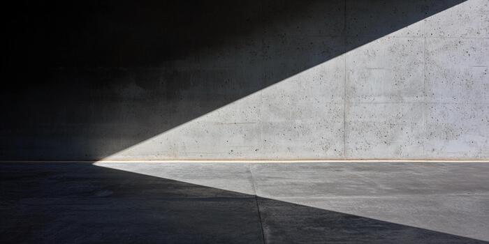 Diagonal light creates striking patterns on a concrete wall in an indoor space photo