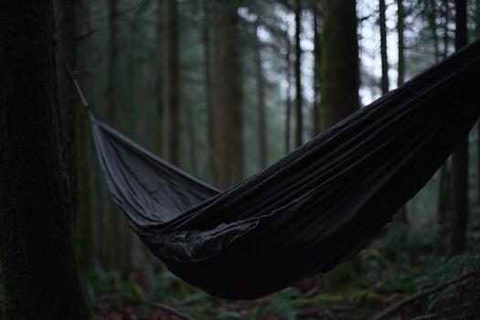 Relaxing in a black hammock among tall trees in a serene forest setting photo