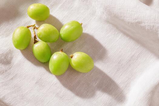 Scattered green grapes on a linen cloth create a minimalist aesthetic photo