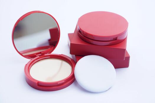 Red compact powder case with mirror, sponge applicator, and product box displayed on a clean white background, showcasing cosmetic packaging design and beauty product presentation in a minimal style. photo