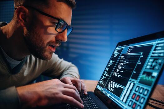 Man coding on laptop screen at night photo