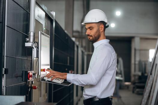 Engineer with laptop in manufacturing facility photo