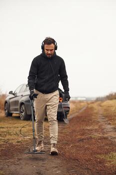 Man metal detecting in field photo