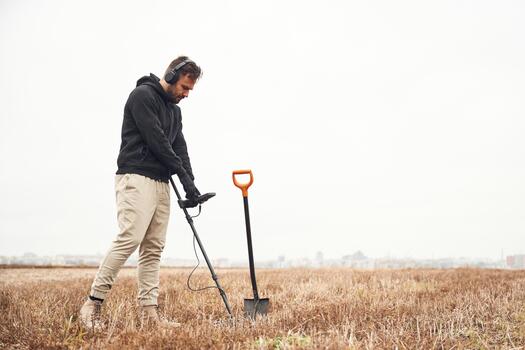 Man with metal detector in field photo