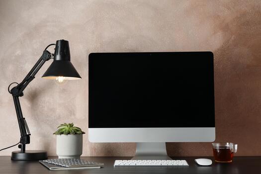 A computer monitor, keyboard, mouse and lamp on a desk photo