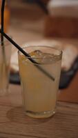 Chilled lemonade with citrus and ice cubes, Cool lemon drink with straw on wooden surface in summer video