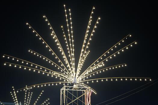 Decorative light display at night with strands of glowing bulbs creating a starburst effect against a dark sky during a festive celebration event photo