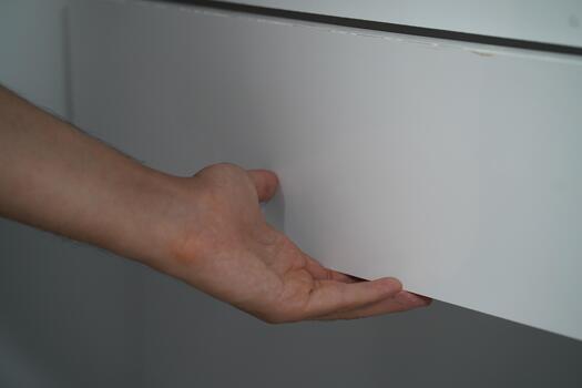 Close Up of a Hand Reaching for a White Drawer with Smooth Surface in a Minimalistic Interior Setting for Stylish Home Organization photo