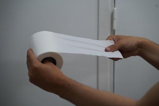 Person Holding a Roll of Paper Towel with a Smooth Sheet Unrolled Against a Simple Background in a Indoor Setting photo