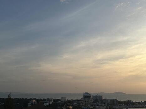 Serene Coastal Skyline at Dusk with Soft Clouds Over Tranquil Waters and Urban Development in the Foreground Illuminated by Fading Evening Light photo