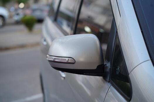 Close-Up of a Silver Car Side Mirror Capturing Reflections on a Sunny Day in an Urban Setting with Soft Background Blurs and Interesting Details photo