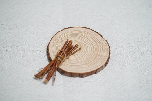 Natural wooden slice with tree rings showcasing intricate patterns on a textured fabric background with bundle of twigs arranged nearby photo