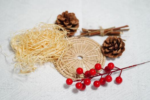 Natural Decorative Elements for Rustic Crafts Featuring Pinecones, Straw, Rattan Mat, Cinnamon Sticks, and Red Berries on White Background photo