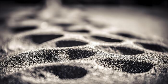 A close up abstract pattern of textured sand with ripples and shadows in a black and white image photo