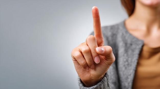 A close-up of a woman's hand raised with one finger pointing upwards, suggesting a pause or attention. photo