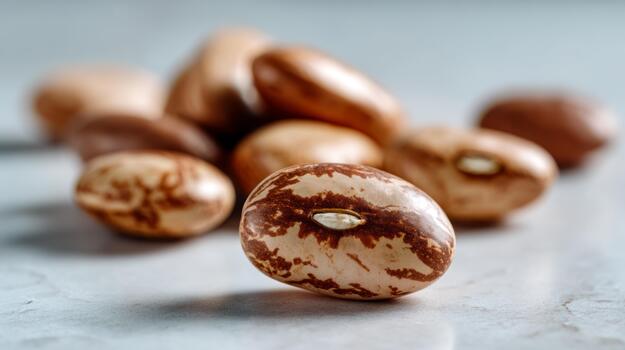 Close-up of various speckled beans on a textured surface, showcasing their unique patterns and colors. photo