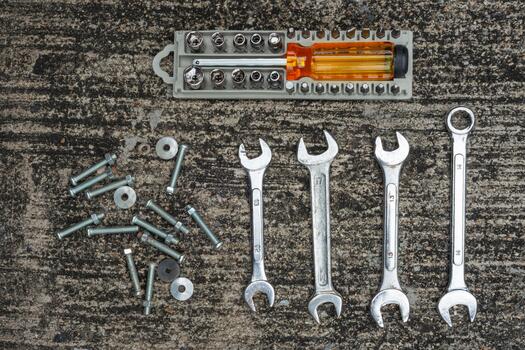 Socket wrenches and hardware tools displayed on a concrete surface during a repair session photo