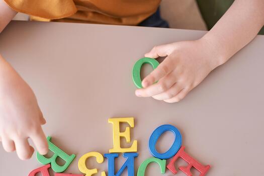 Child's hands playing with colorful alphabet letters on table surface, learning concept. photo