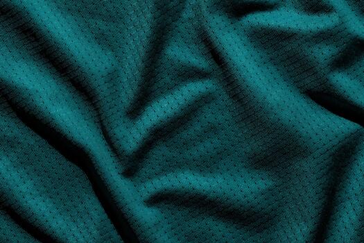 Close-up of wrinkled dark green fabric with texture and subtle pattern in shadowed light. photo