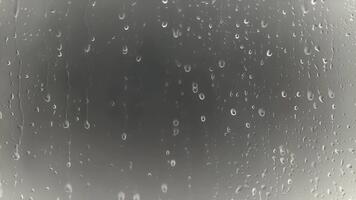 avvicinamento di gocce di pioggia su finestra bicchiere con sfocato sfondo, atmosferico e lunatico effetto video