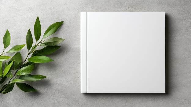 Blank white notebook with green leaves on concrete background photo
