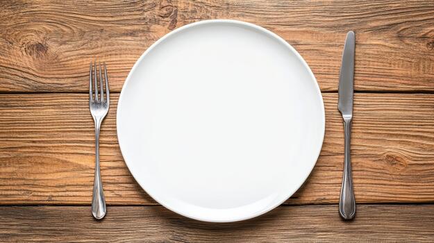 Empty plate, fork and knife on wooden table photo