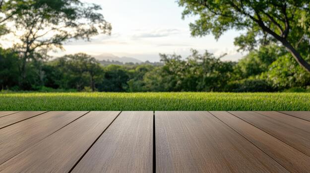 Wooden table top in front of green grass and trees photo