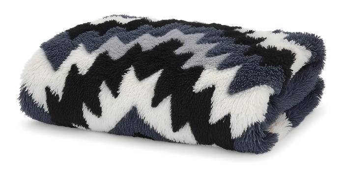 A soft fluffy blanket with a black white and grey chevron zig zag pattern is folded on a white background photo