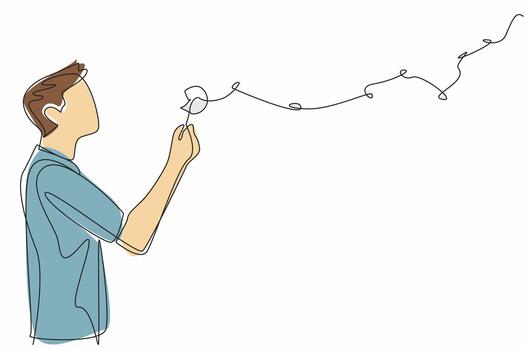 Single one line drawing man in casual clothes blows on dandelion and there are dandelion fragments flying. Blow the hopes sky high. Symbol. World Wish Day. Continuous line design graphic illustration vector
