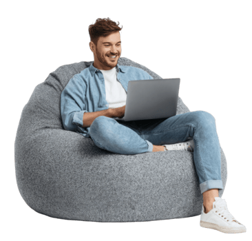 sonriente joven hombre utilizando un ordenador portátil mientras relajante en un cómodo gris frijol bolso silla aislado en transparente antecedentes png