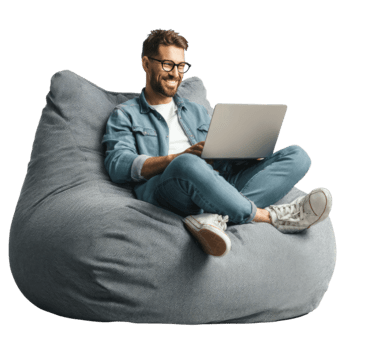 hombre con lentes trabajando en un ordenador portátil mientras relajante en un bolsa de frijoles silla aislado en transparente antecedentes png