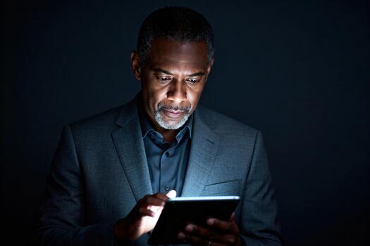 Professional Man In Dark Suit Using Tablet Under Soft Light For Focused Business Work photo