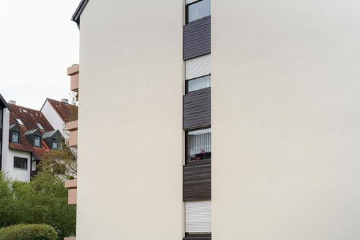 Modern building facade with windows and greenery in an urban setting during cloudy weather photo
